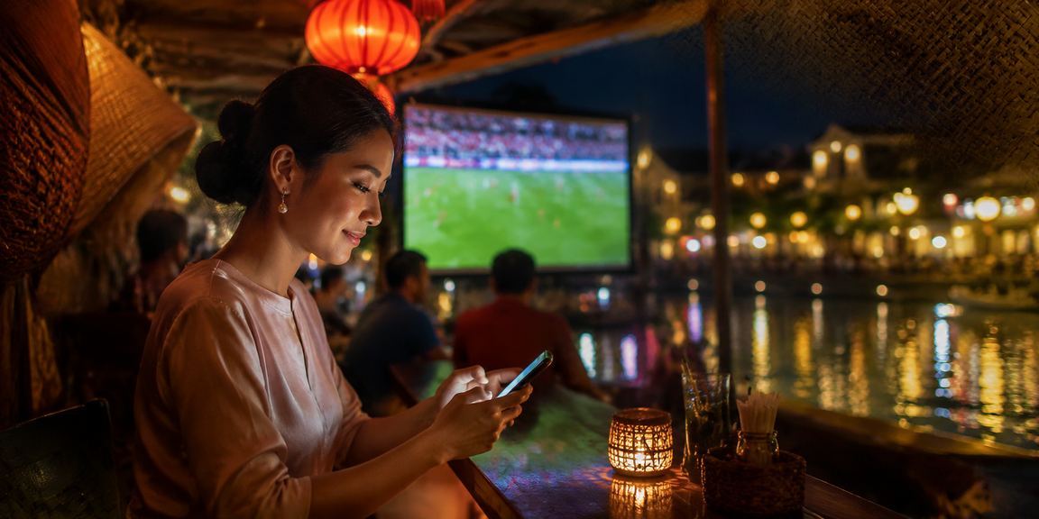 Người dùng Hội An đặt kèo bóng đá trên điện thoại dưới mái nón lá